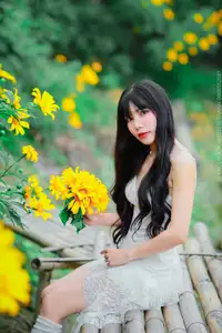 Graceful Young Woman in White Dress Amidst Vibrant Yellow Flowers 1000026997-0