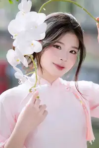 Elegant Vietnamese Beauty: Young Woman Gracefully Posing in Pink Ao Dai with White Orchids 1000026874-13
