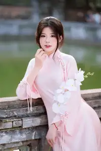 Elegant Vietnamese Beauty: Young Woman Gracefully Posing in Pink Ao Dai with White Orchids 1000026874-1